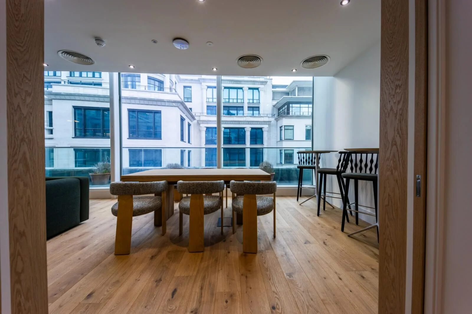 Oak collaboration table and counter seating framed by a large City-facing window